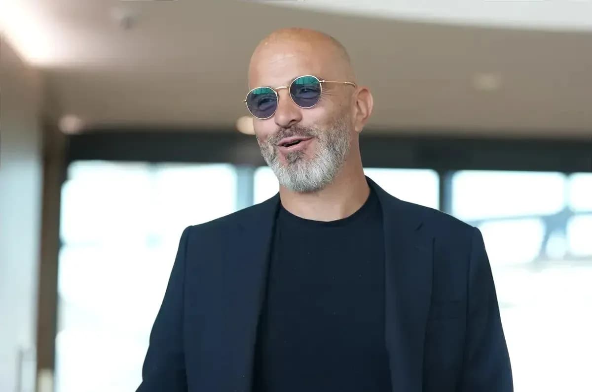 Person wearing sunglasses and a dark blazer indoors