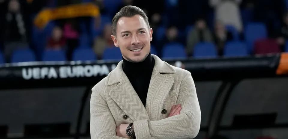 Man in stylish coat smiling during a match
