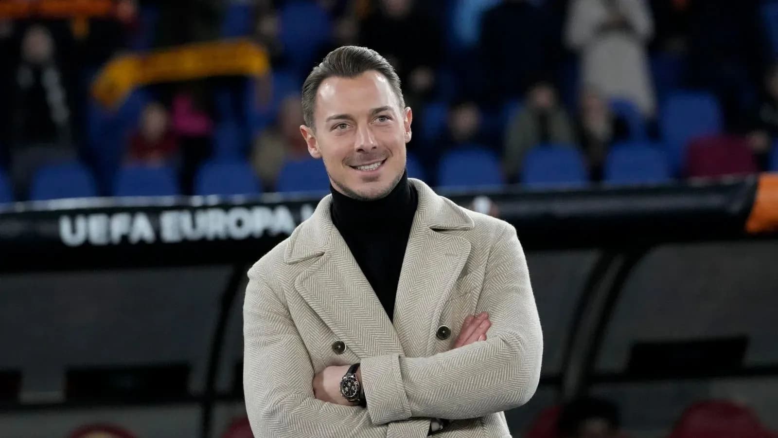 Man in stylish coat smiling during a match