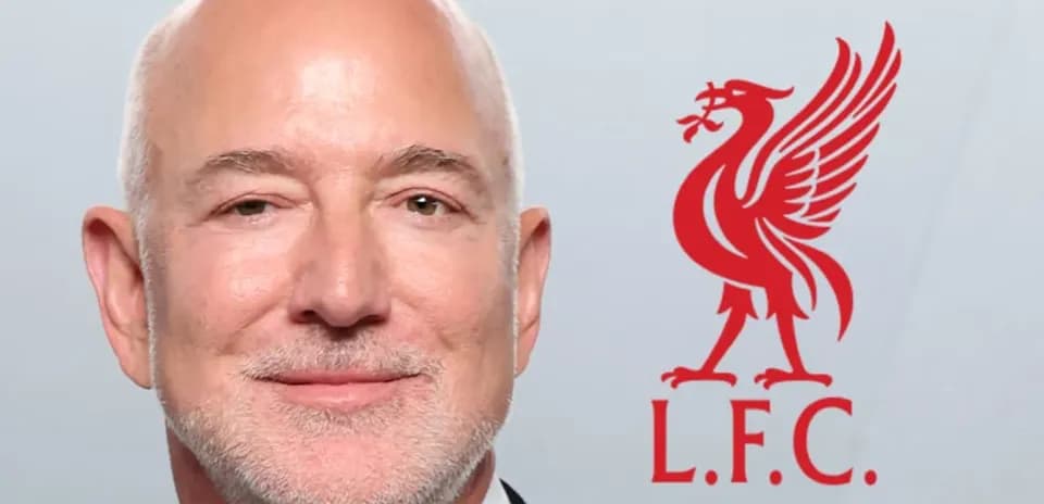 Man smiling with Liverpool FC logo in background