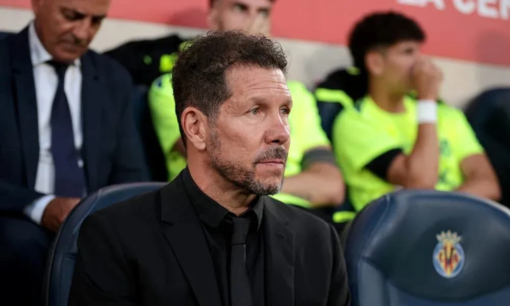 Coach seated on bench during match with players