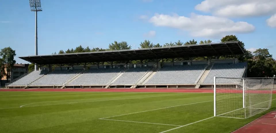 Empty football stadium with green pitch and goalpost
