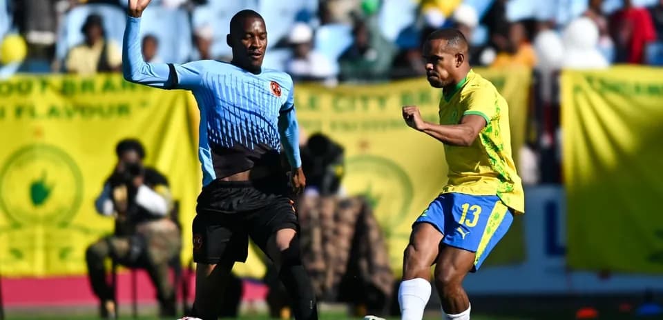 Player in yellow kicking ball, defender in blue nearby