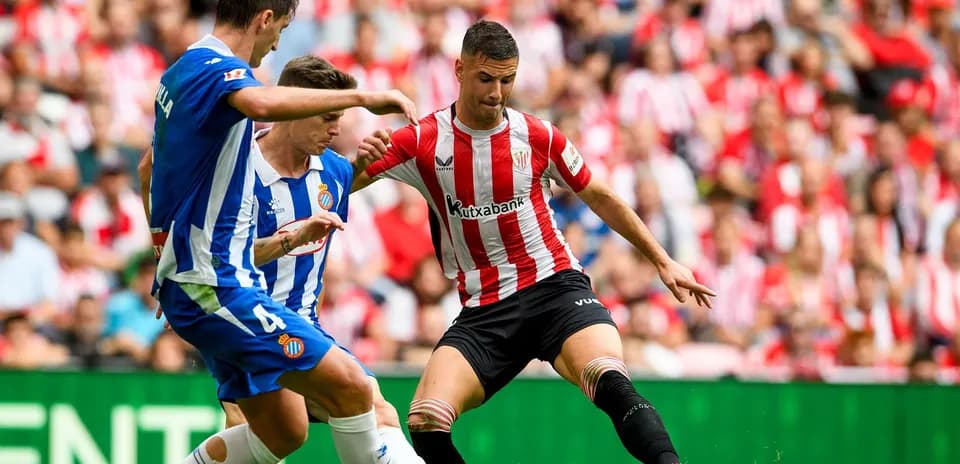 Espanyol players challenging Athletic Club opponent