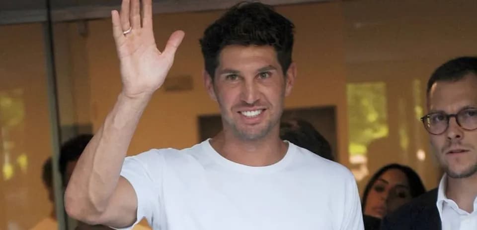 Man in white shirt waving, surrounded by people
