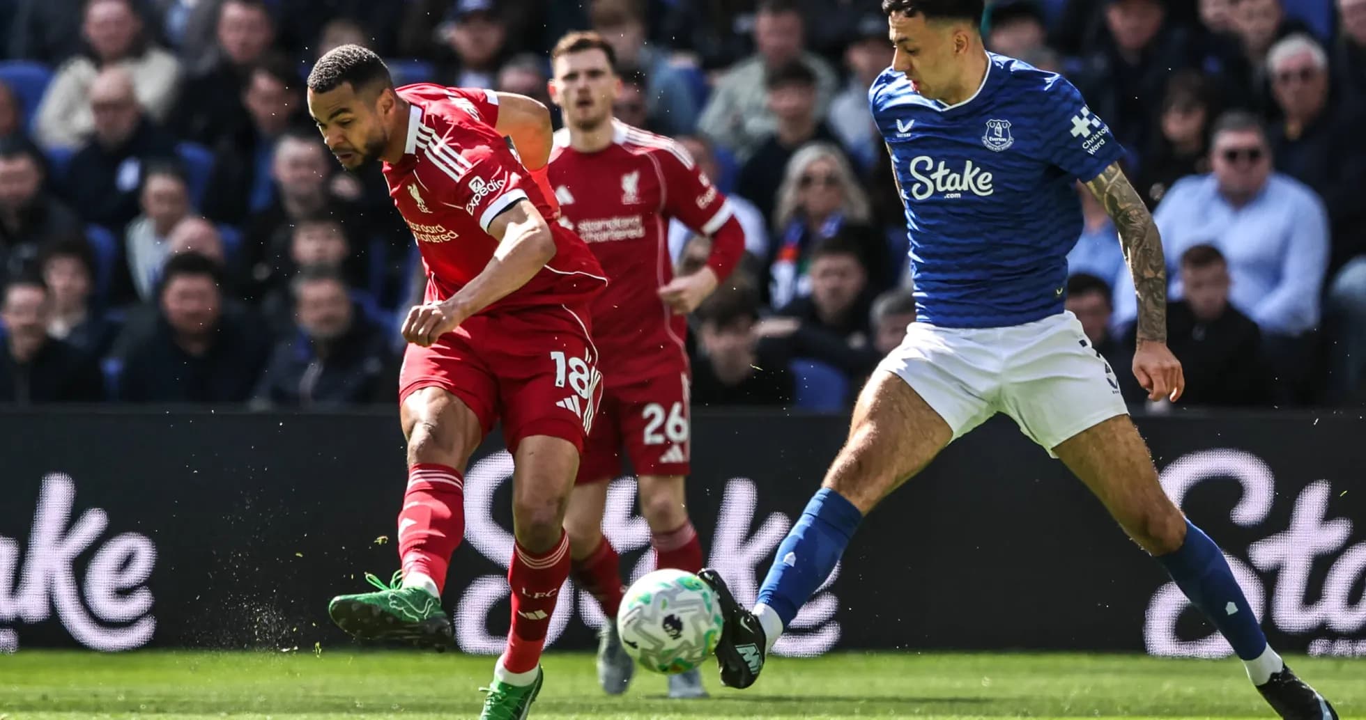 Liverpool player dribbling past Everton defender during match