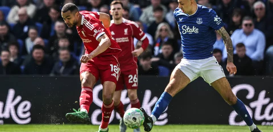 Liverpool player dribbling past Everton defender during match
