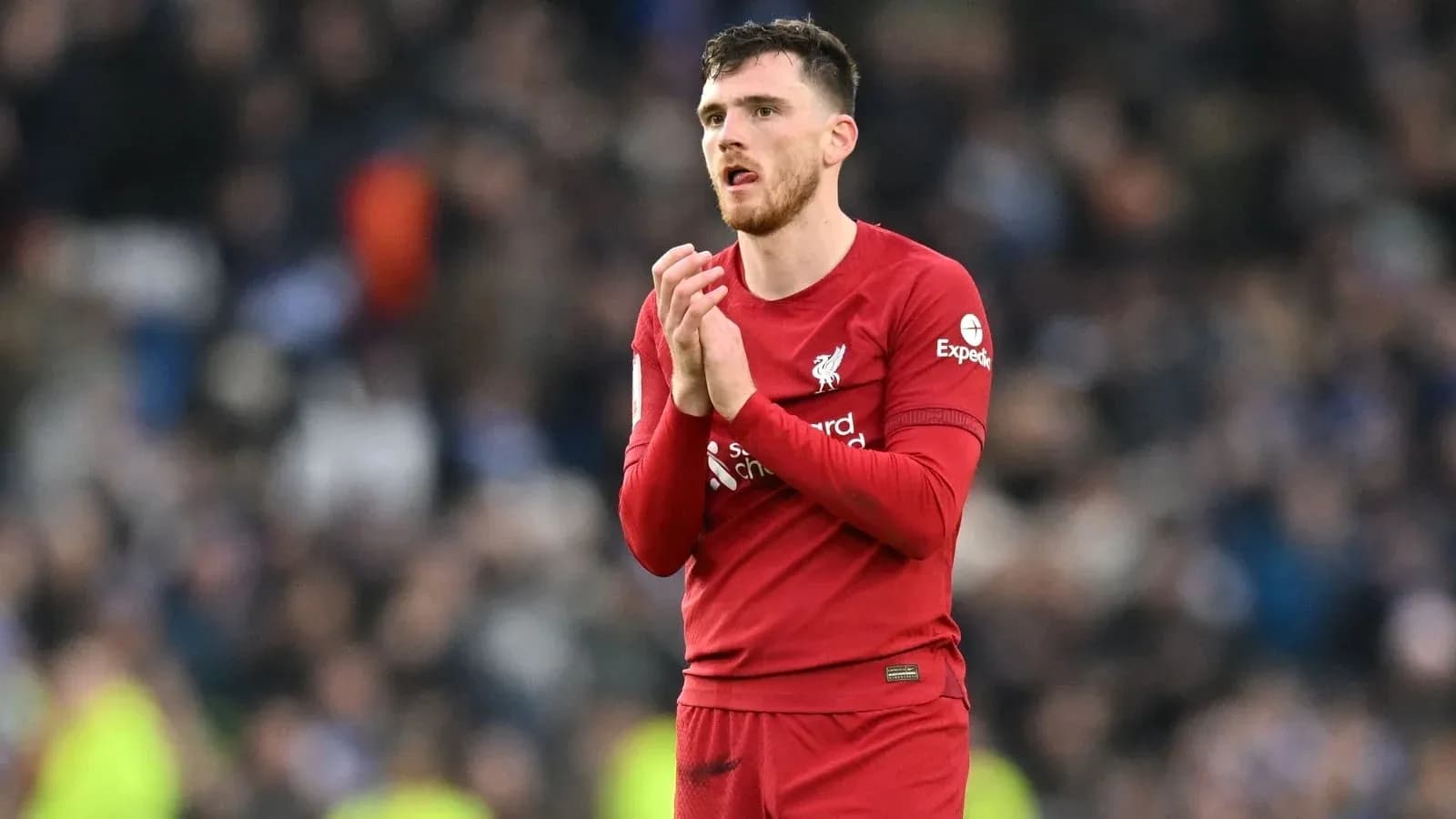 Player in Liverpool kit applauding fans after match