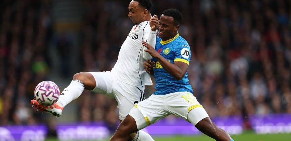 Fulham player challenging Wolves player for the ball