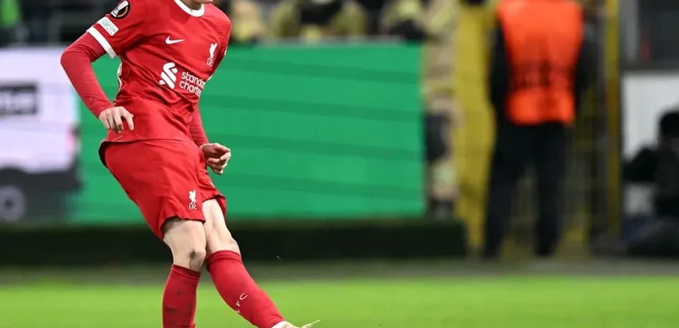Player in red kit kicking the ball on field
