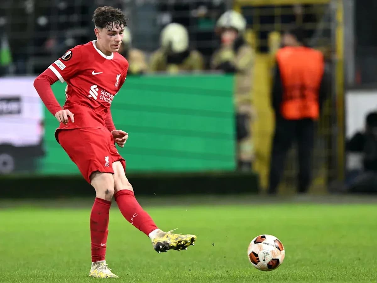 Player in red kit kicking the ball on field