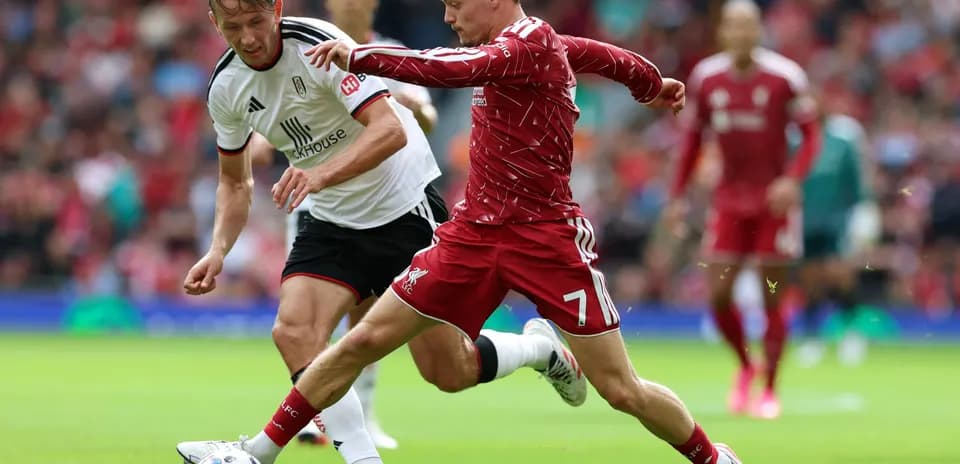 Liverpool player challenging Fulham opponent for the ball