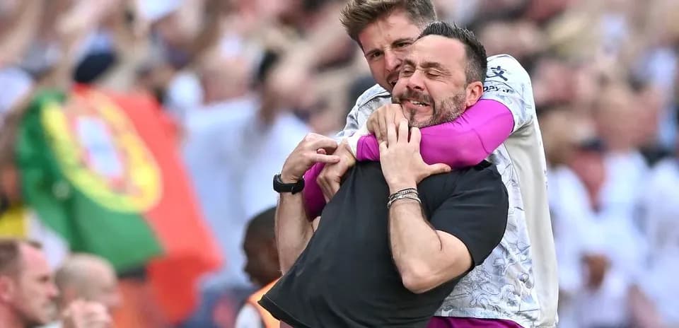 Two coaches celebrating a goal in the stands