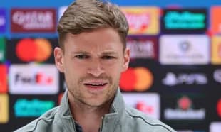 Man speaking at press conference with sponsor logos