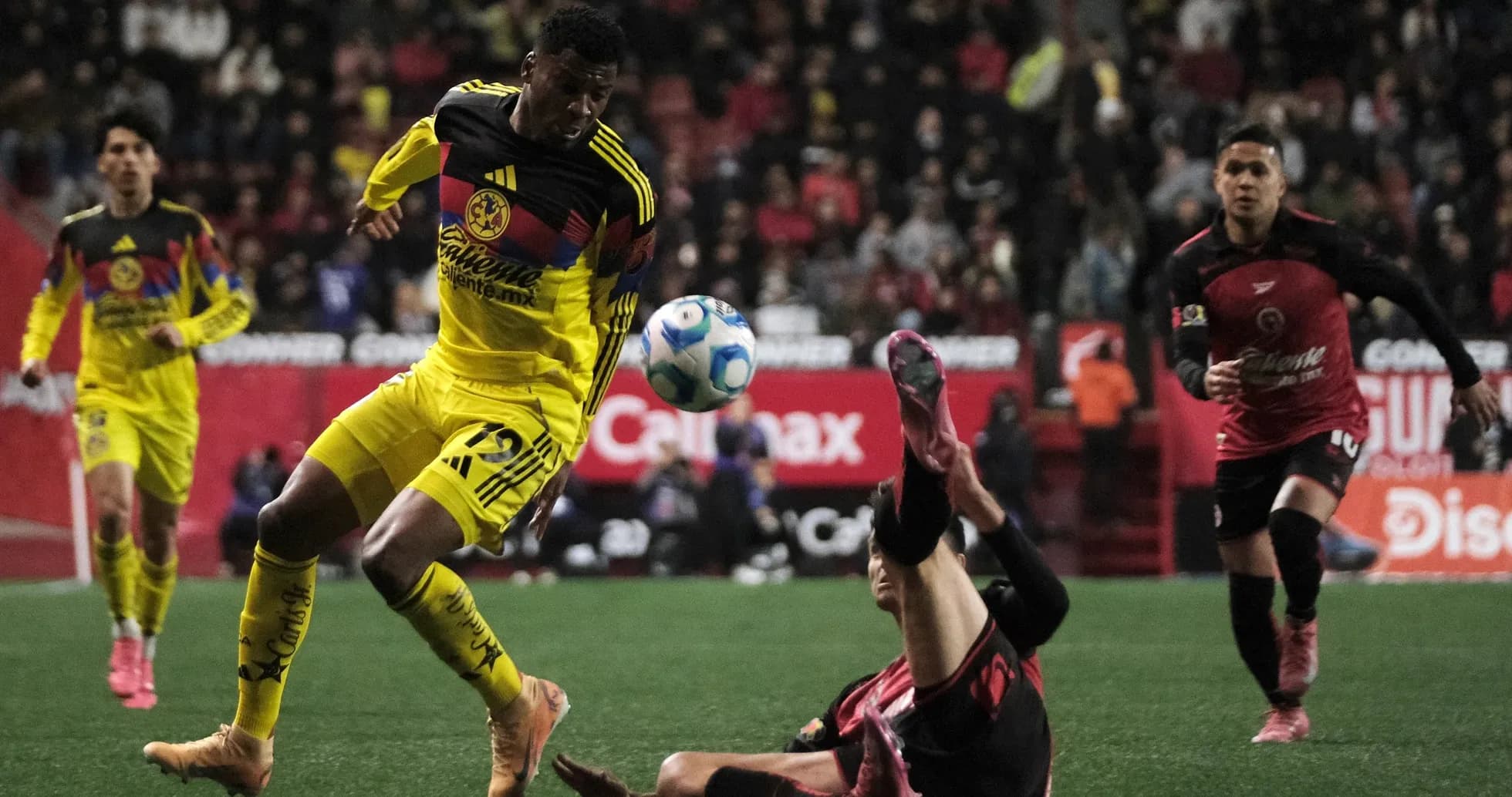 Club America player dribbling past Club Tijuana defender