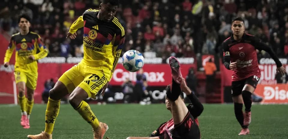 Club America player dribbling past Club Tijuana defender