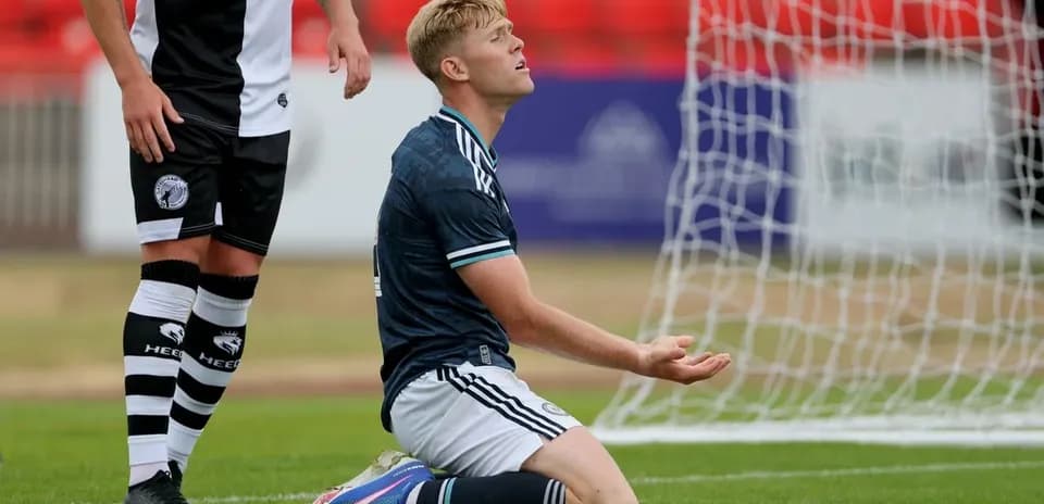 Player kneeling on pitch with hands raised