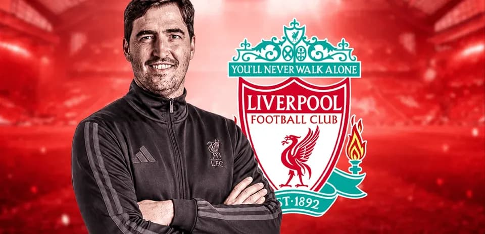 Coach posing in front of Liverpool FC logo