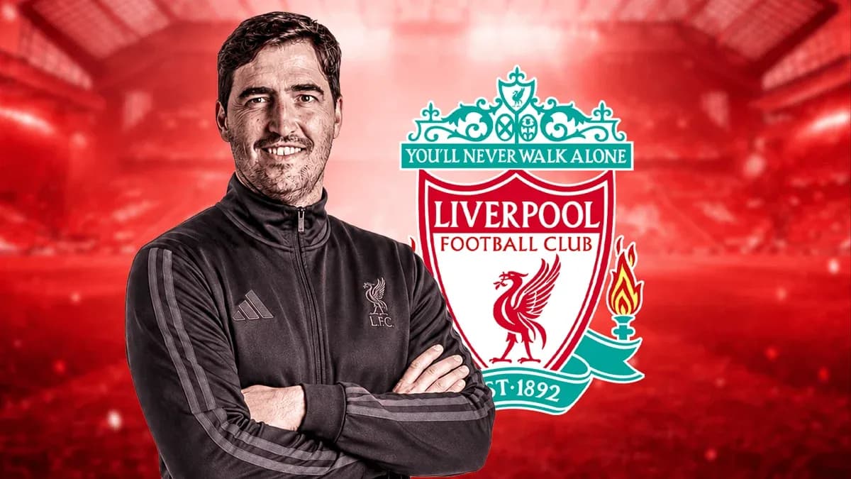 Coach posing in front of Liverpool FC logo
