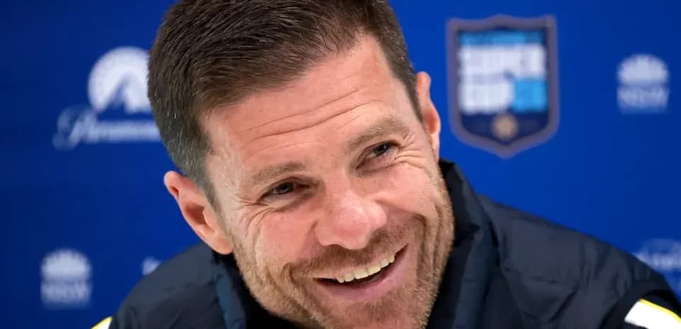 Coach smiling during press conference with backdrop
