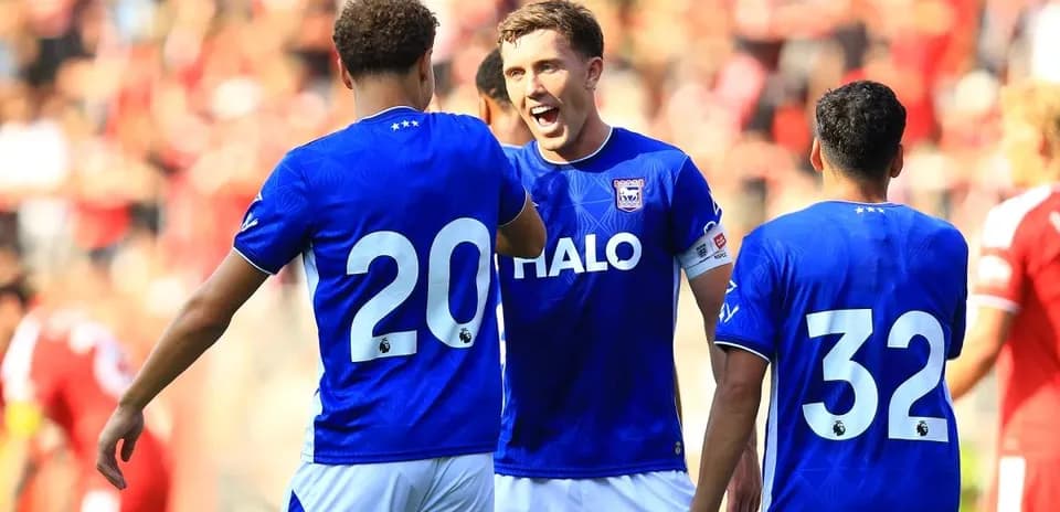 Three players celebrating in blue jerseys on field