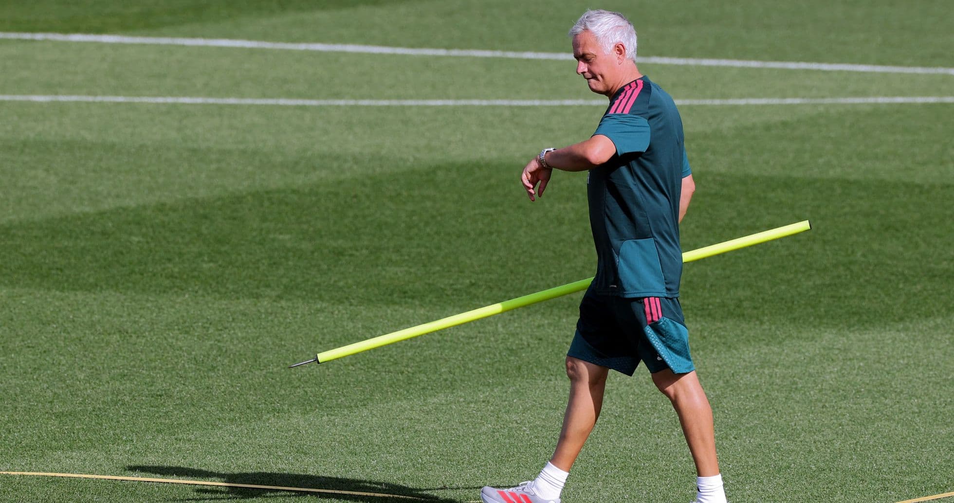 Coach walking with training pole on field