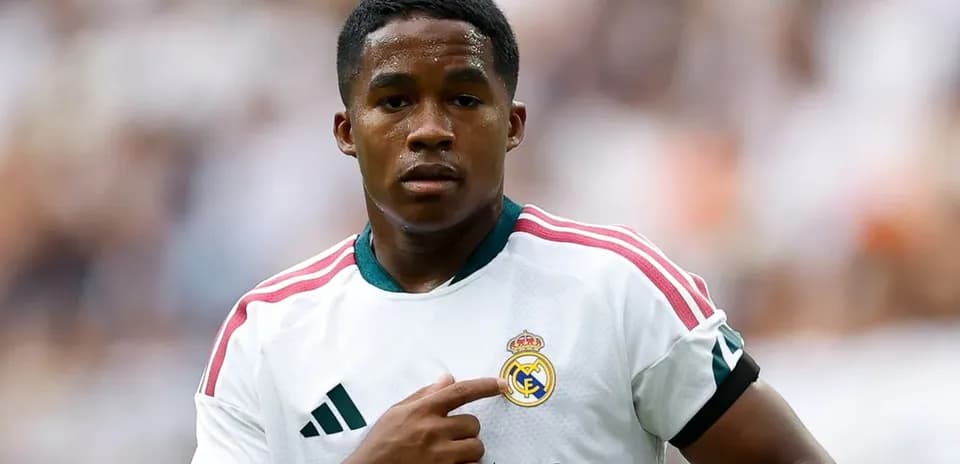Player pointing to Real Madrid club badge on jersey