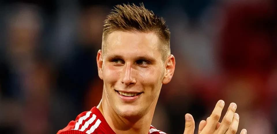 Player in red jersey smiling and applauding fans