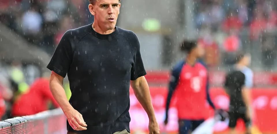 Coach walking on sideline during rainy match