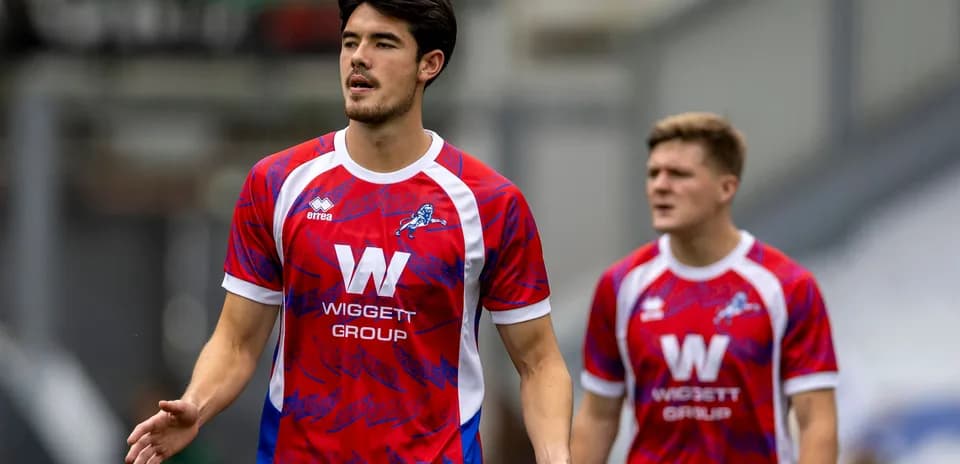 Two players in red and blue football kits walking