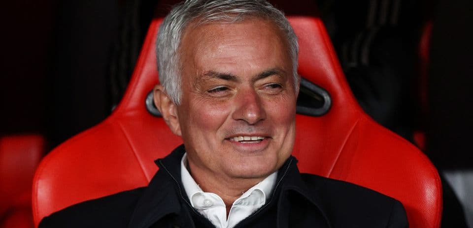 Coach seated in red stadium dugout during match