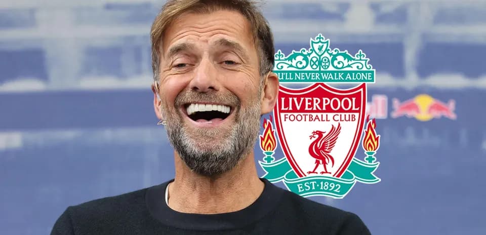 Manager smiling during press conference with Liverpool logo