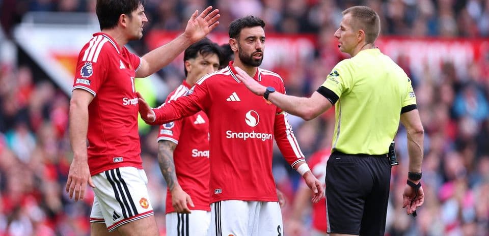 Manchester United players discussing with the referee