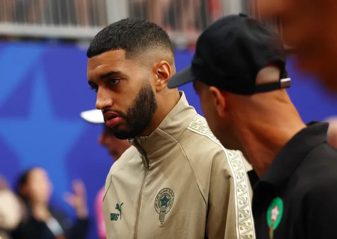 Player in warm-up jacket conversing with staff member