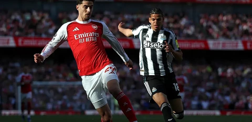 Arsenal player challenging Newcastle opponent for the ball
