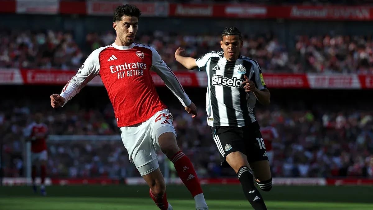 Arsenal player challenging Newcastle opponent for the ball