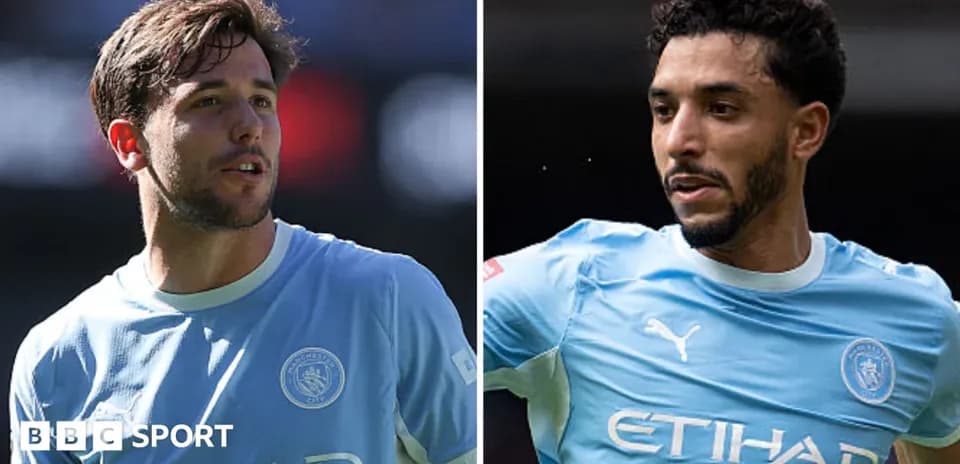 Two Manchester City players in light blue jerseys
