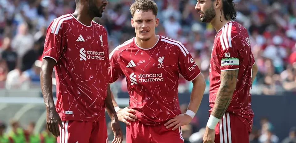 Three Liverpool players discussing strategy on field