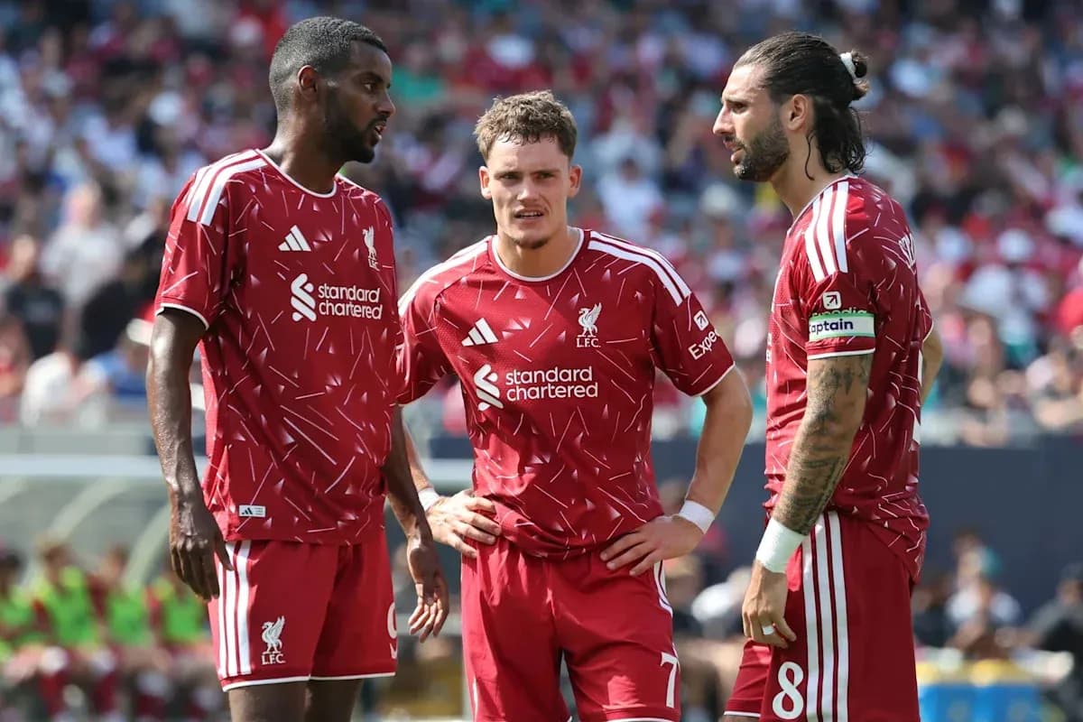 Three Liverpool players discussing strategy on field