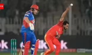 Bowler delivering a ball while batsman prepares to hit