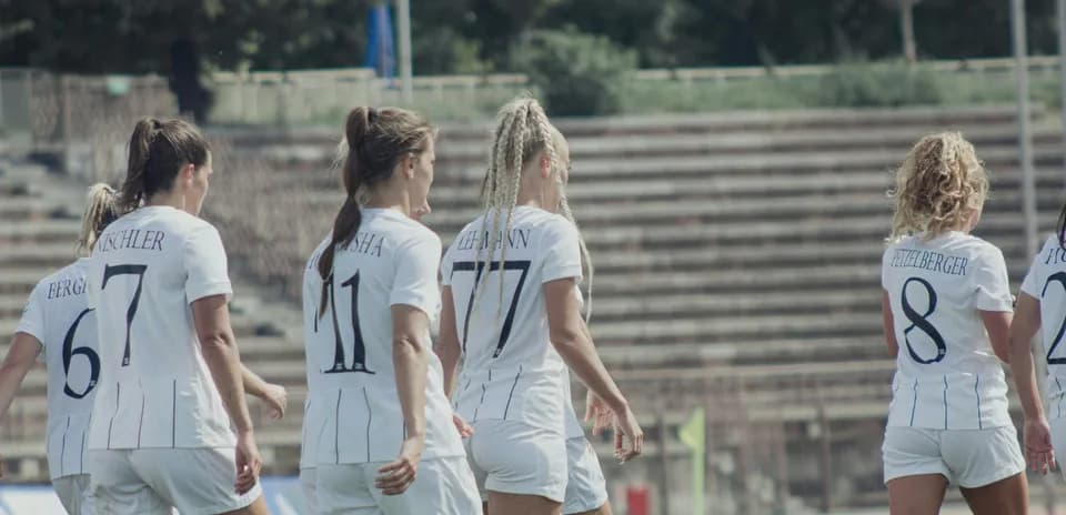 Players walking on the pitch in white uniforms