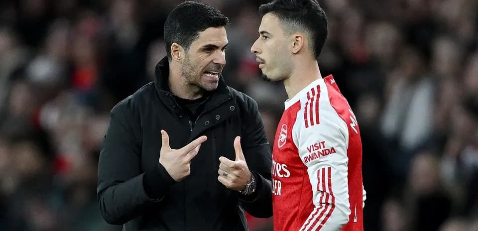 Manager discussing tactics with player on pitch