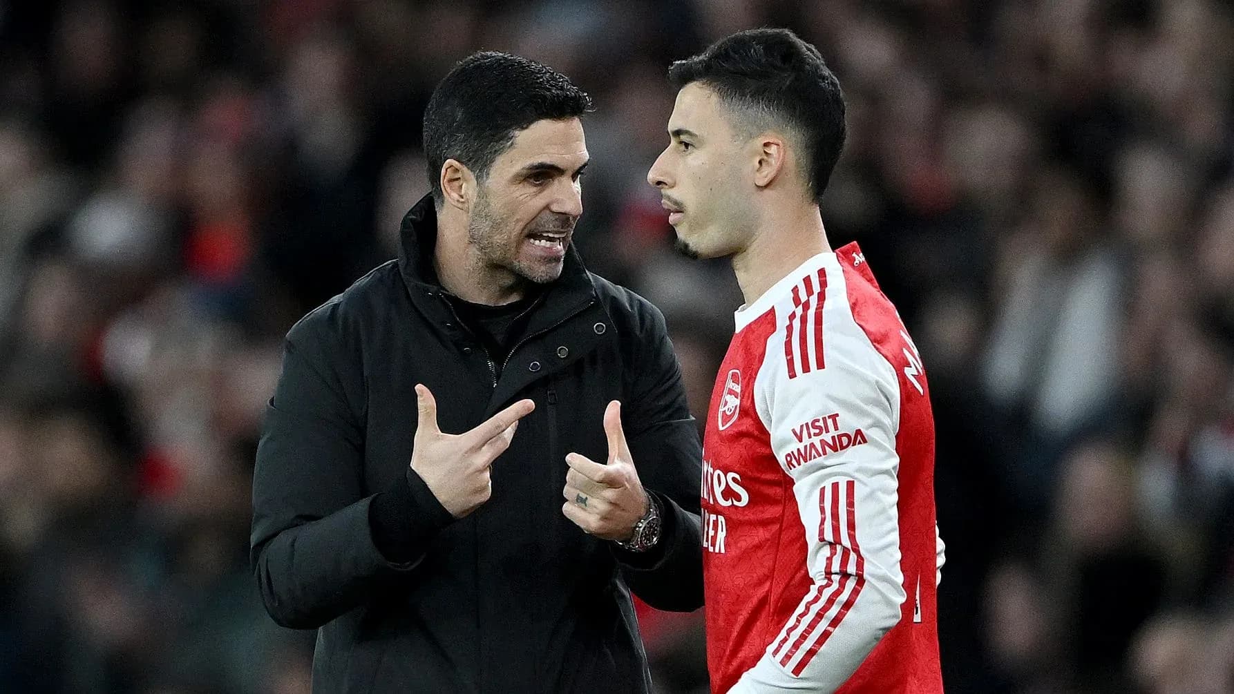 Manager discussing tactics with player on pitch