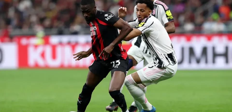 Juventus player tackling AC Milan opponent