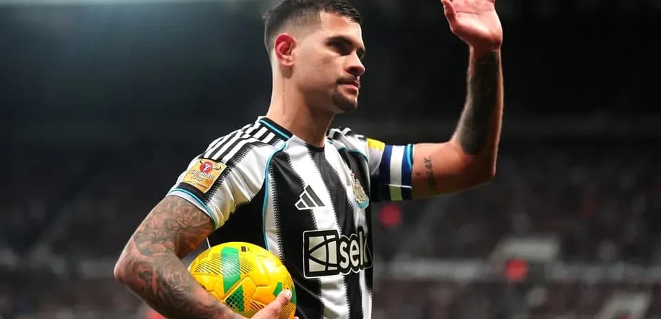 Player waving while holding a football on pitch