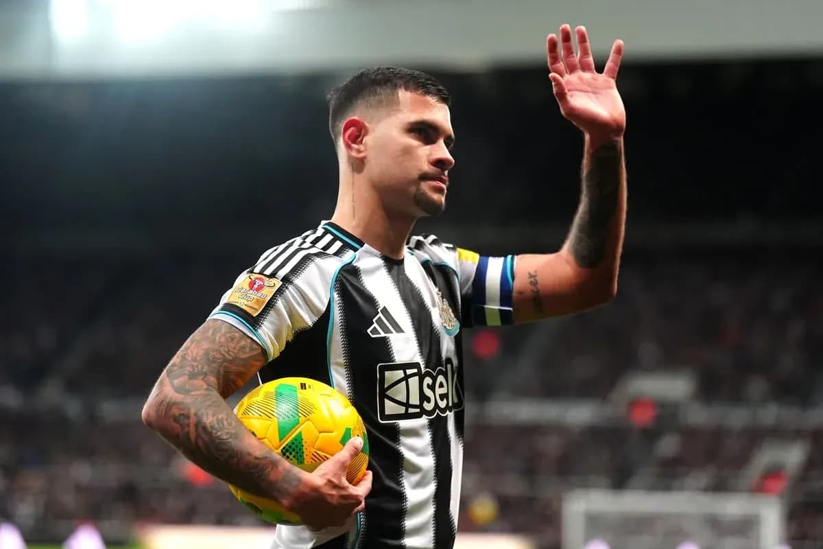 Player waving while holding a football on pitch