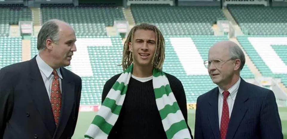 New player holding scarf with club officials at stadium