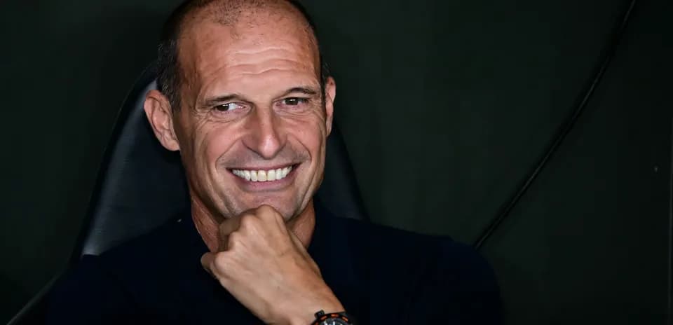 Smiling coach seated, hand on chin