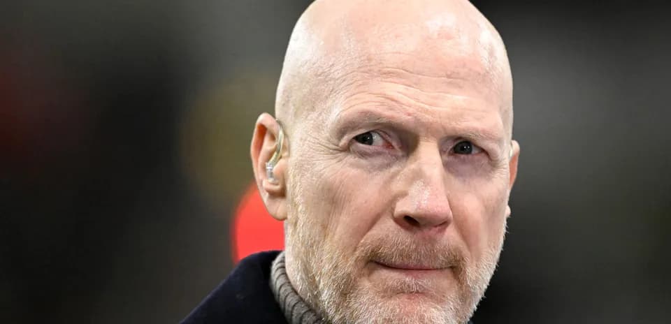 Bald man with earpiece looking thoughtfully