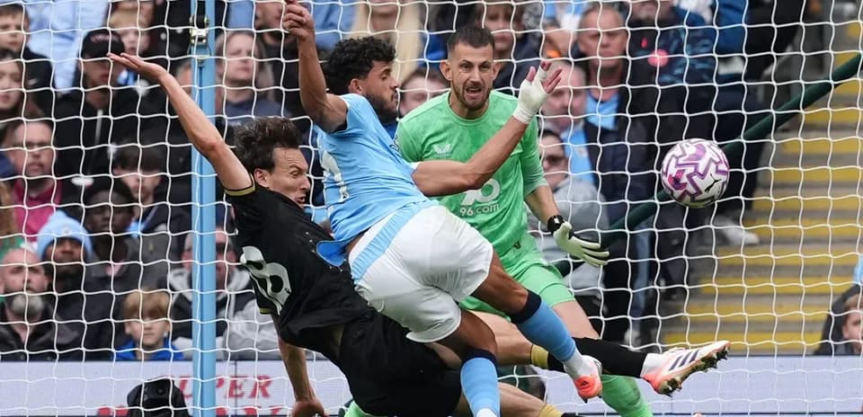 Goalkeeper and defenders contesting a shot on goal